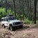 A 4 by 4 vehicle drives over a rough road in a forest